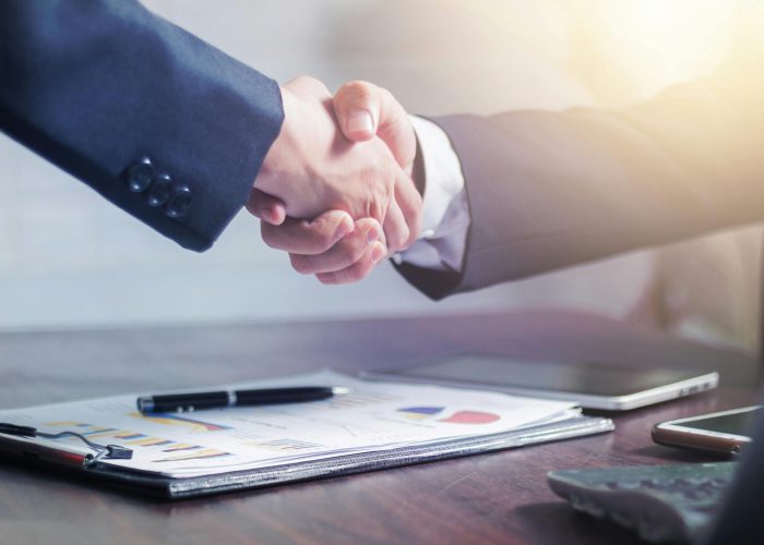 Professional handshake agreement over business charts in an office setting.